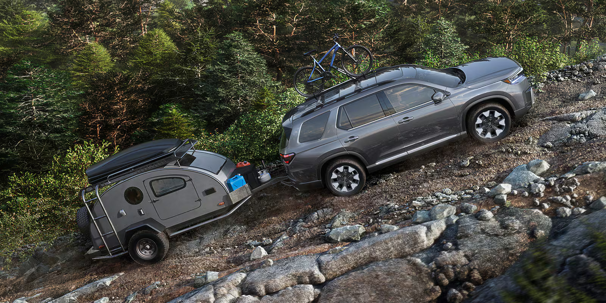 The 2026 Honda Pilot towing a camper up a slope